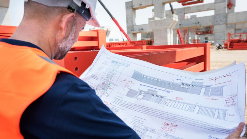 Ingegnere in cantiere analizza un progetto tecnico per la costruzione di un data center e infrastrutture digitali avanzate